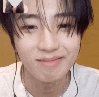 a close up of a young man wearing headphones and a white shirt smiling .