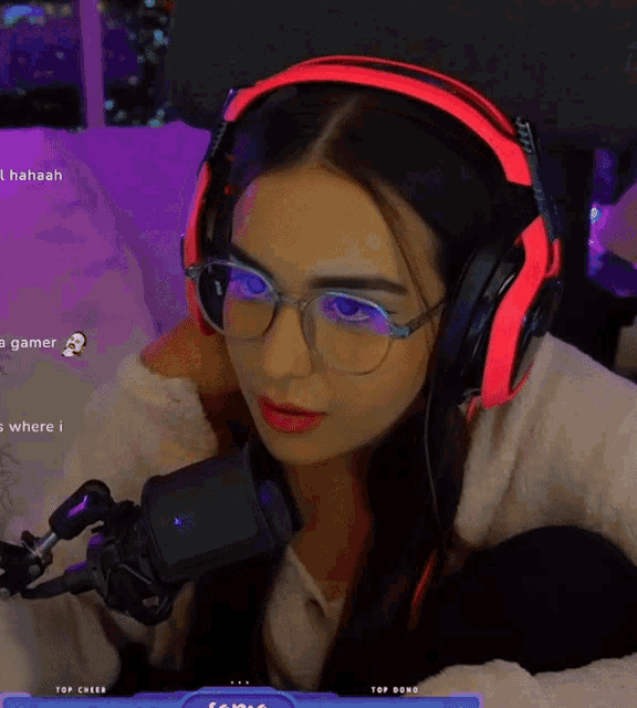 a woman wearing headphones and glasses is sitting in front of a microphone with the words " top cheer " on the bottom