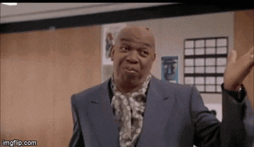 a man in a suit and scarf is making a funny face with his hands in the air .