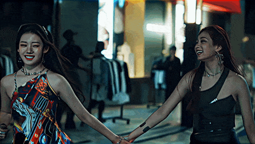 two women holding hands and smiling in front of a store