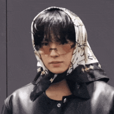 a man wearing sunglasses and a scarf around his head looks at the camera