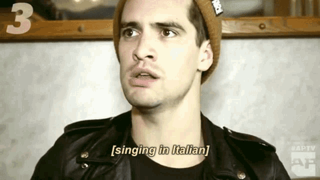 a man wearing a beanie and a leather jacket is singing in italian