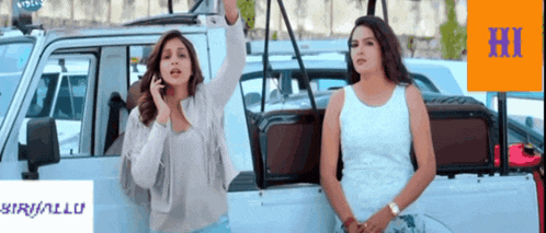 two women are standing in front of a white car with the word hi on the bottom