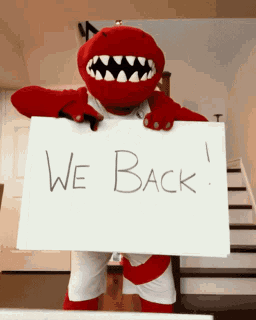 a mascot is holding up a sign that says we back