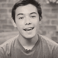 a young man is smiling in a black and white photo while wearing a microphone .