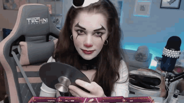 a woman in a clown costume is holding a cd in front of a techni chair