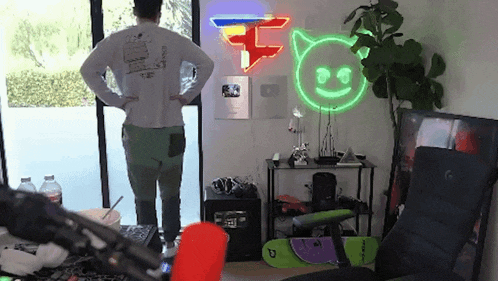 a man is standing in a room with a neon sign that says faze clan