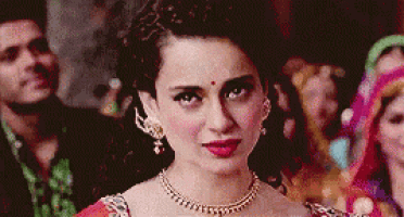 a woman wearing a necklace and earrings is standing in a crowd .
