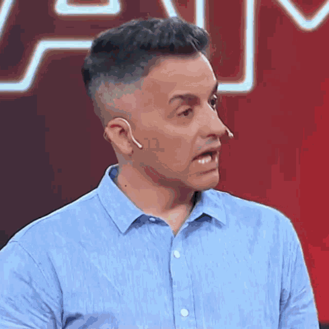 a man wearing a blue shirt and a microphone is making a funny face .
