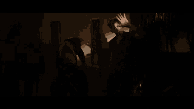 a man is standing in a dark room talking to another man in a dark room .