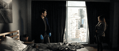 a man in blue gloves stands next to a woman in a dark room
