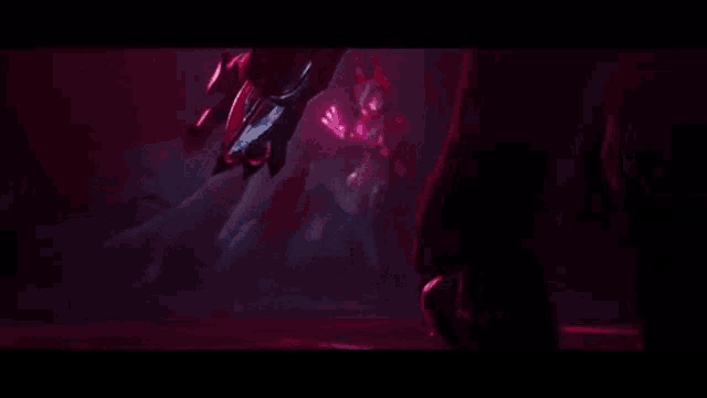 a person is holding a red sword in a dark room .