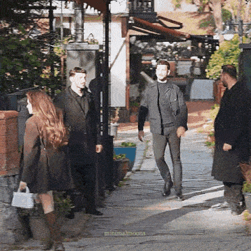 a group of people are standing on a sidewalk in front of a restaurant .