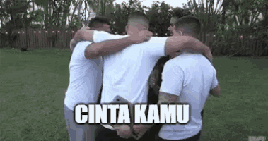 a group of men are hugging each other in a field with the words cinta kamu written above them .