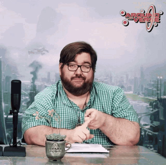 a man in a green plaid shirt sits at a desk in front of a sign that says " arguing over "
