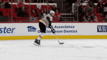 a hockey player in front of a wall that says tim associates on it
