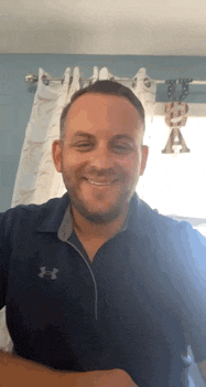 a man wearing a blue under armour shirt is smiling in front of a window