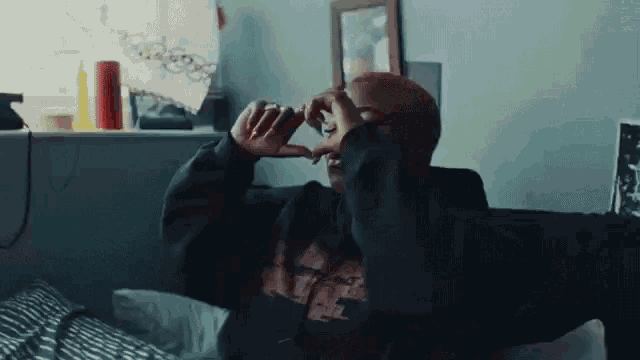 a man with red hair is sitting on a couch with his hands on his nose .