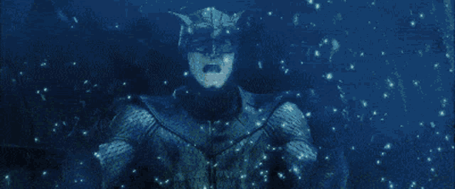 a close up of a man in a batman costume screaming in the dark .