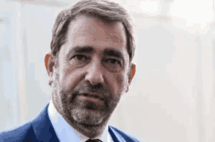 a man with a beard is wearing a blue suit and tie .