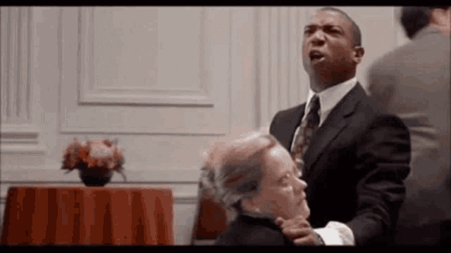 a man in a suit and tie is holding a woman 's neck