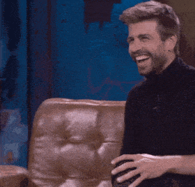 a man with a beard is smiling while sitting on a brown couch