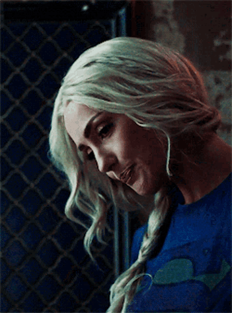 a woman with blonde hair is wearing a blue shirt and braided hair .