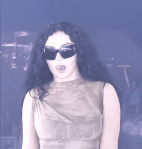 a woman wearing sunglasses and a sleeveless top