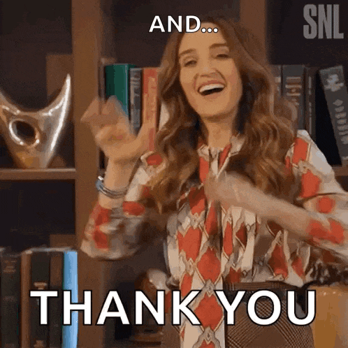 a woman is standing in front of a bookshelf with her hands in the air and says `` and ... thank you '' .