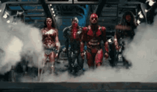 a group of superheroes are standing next to each other in a room with smoke coming out of them .
