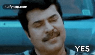 a man with a mustache is making a funny face with his eyes closed and the word yes written below him .