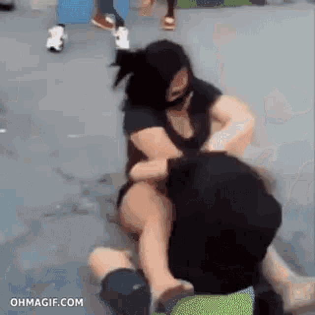 a man and a woman are wrestling on the ground . the woman is wearing a mask .