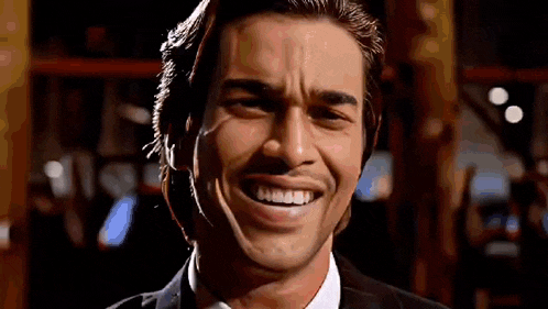 a man in a suit and tie is smiling with his mouth open .