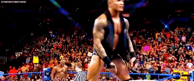 a man is standing in a wrestling ring with a crowd watching .