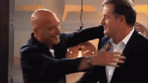 a man in a suit is hugging another man in a suit .