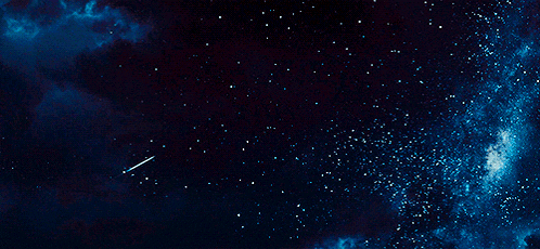 a shooting star flies through a dark night sky