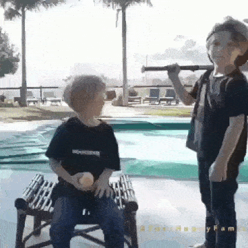 a boy holding a telescope while another boy sits in a chair