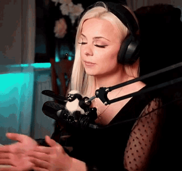 a woman wearing headphones is sitting in front of a microphone with her eyes closed