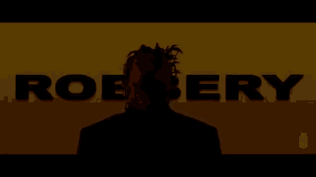 a man in a suit is standing in front of a yellow and orange background with the word robbery written on it .