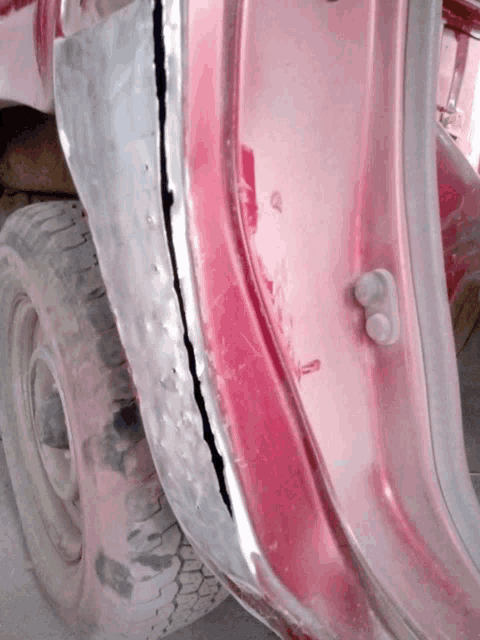 a close up of a red car door with a tire