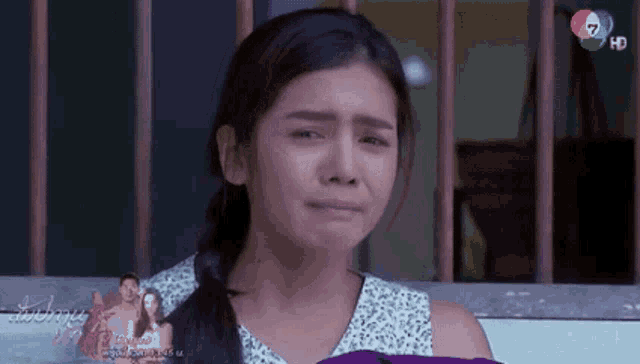 a woman is crying in front of a tv screen with the number 7 on it