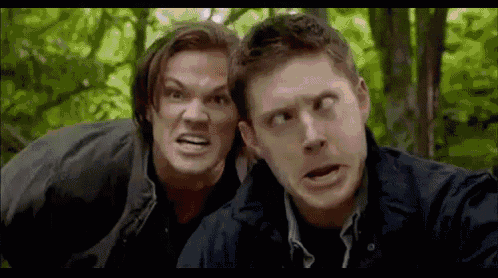 two men are making funny faces in front of trees .