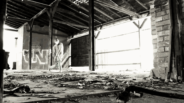 a black and white photo of a man standing in a room with graffiti on the wall that says un