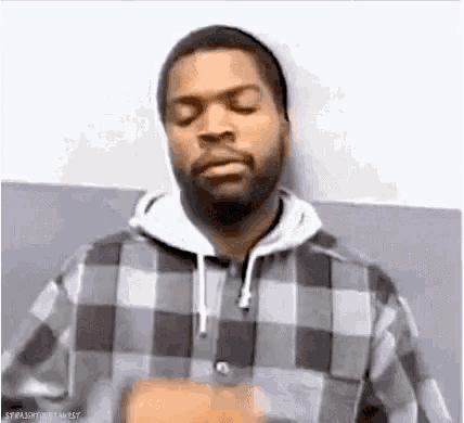 a man with a beard is wearing a plaid shirt and a white hoodie .