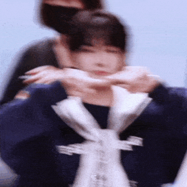 a blurry picture of a person making a heart shape with their hands