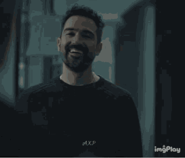 a man with a beard wearing a black shirt that says axp