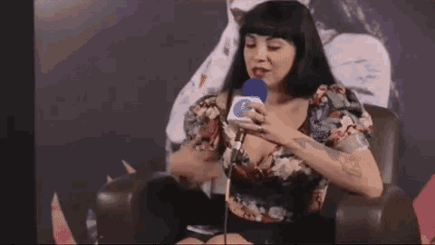 a woman is sitting in a chair holding a microphone in her hand .