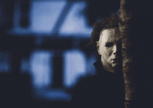 a person with a mask on their face standing in the dark