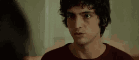 a man with curly hair is making a funny face and talking in a language other than english .