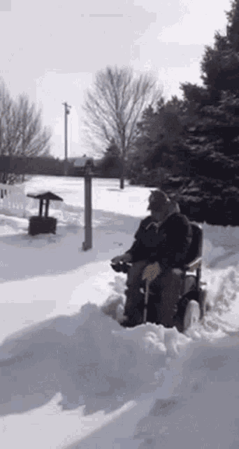 a man in a wheelchair is driving a snow blower